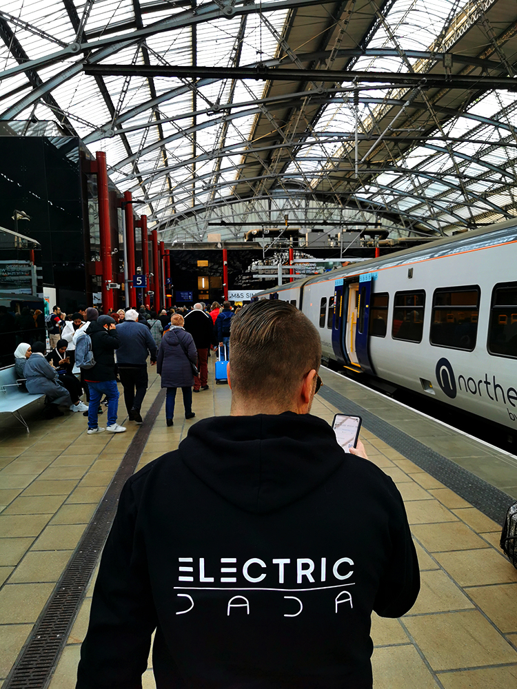 jand de vice micha schrodt at Manchester Piccadilly station. he is wearing a black hoodie by electric dada. this hoodie can be bought in the shop of electric dada.